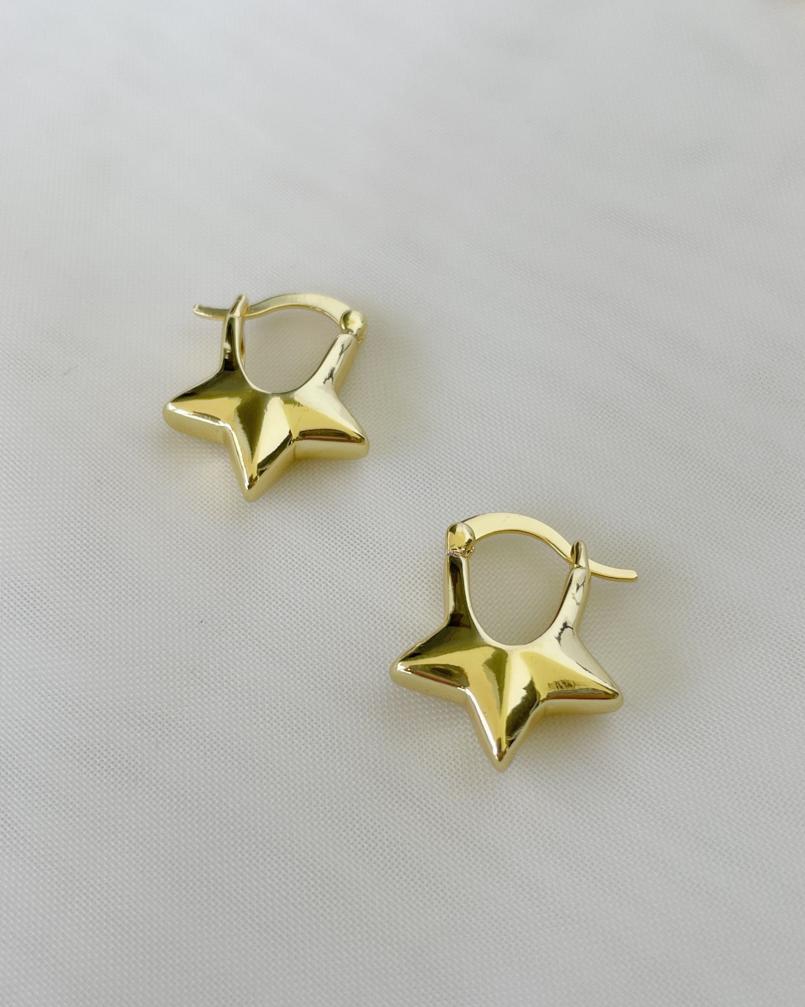 Gold star-shaped earrings on a white background