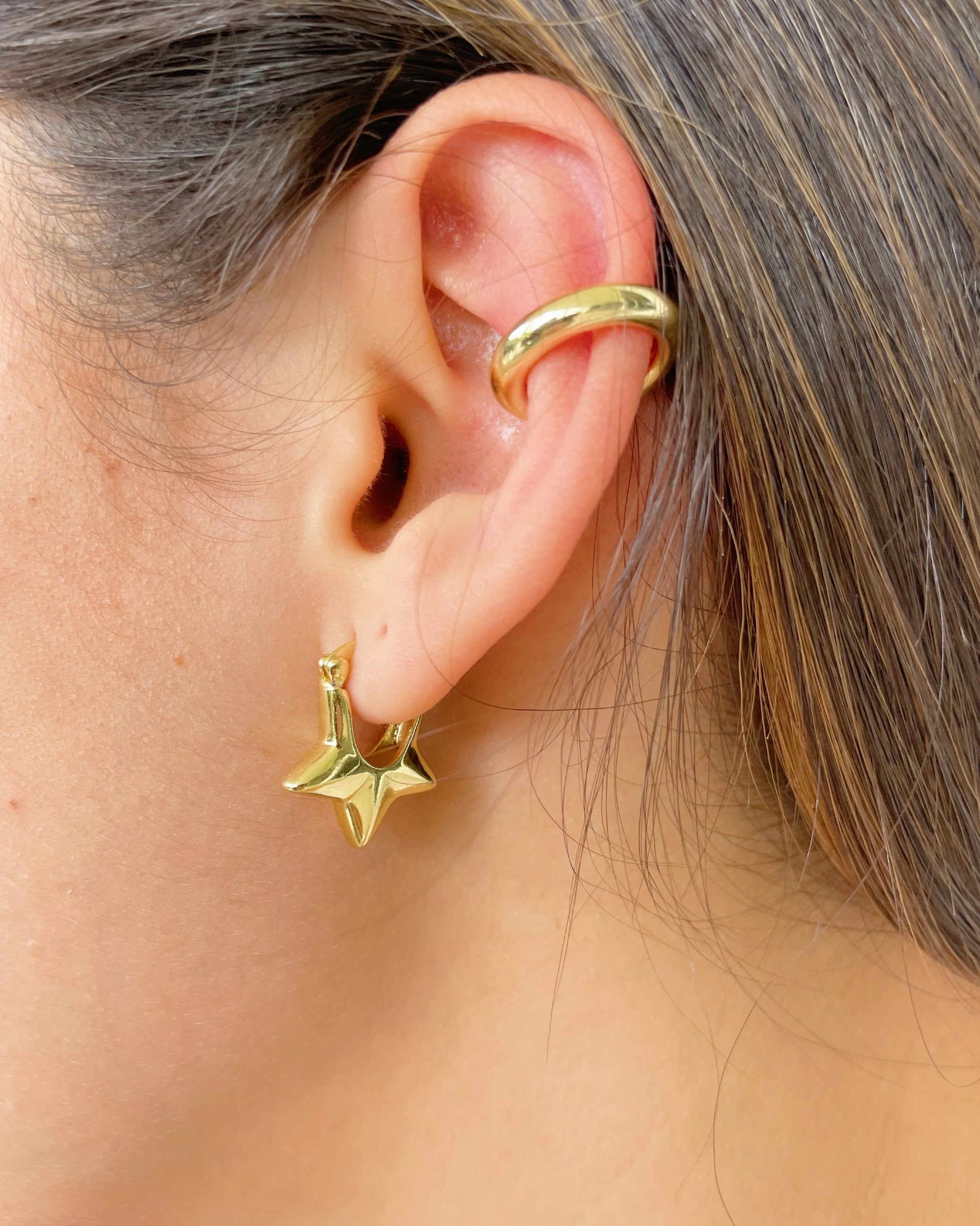Gold hoop earring worn by a person.